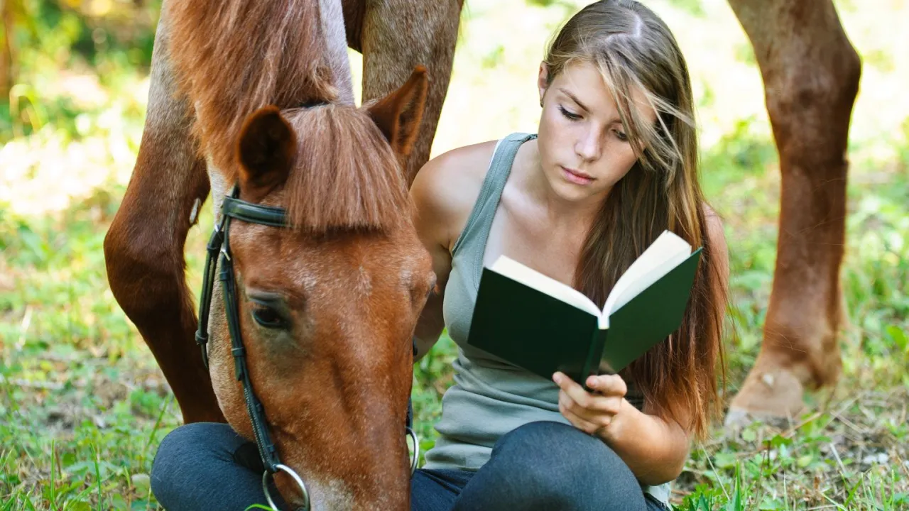 dziewczynka czytająca książkę o koniach