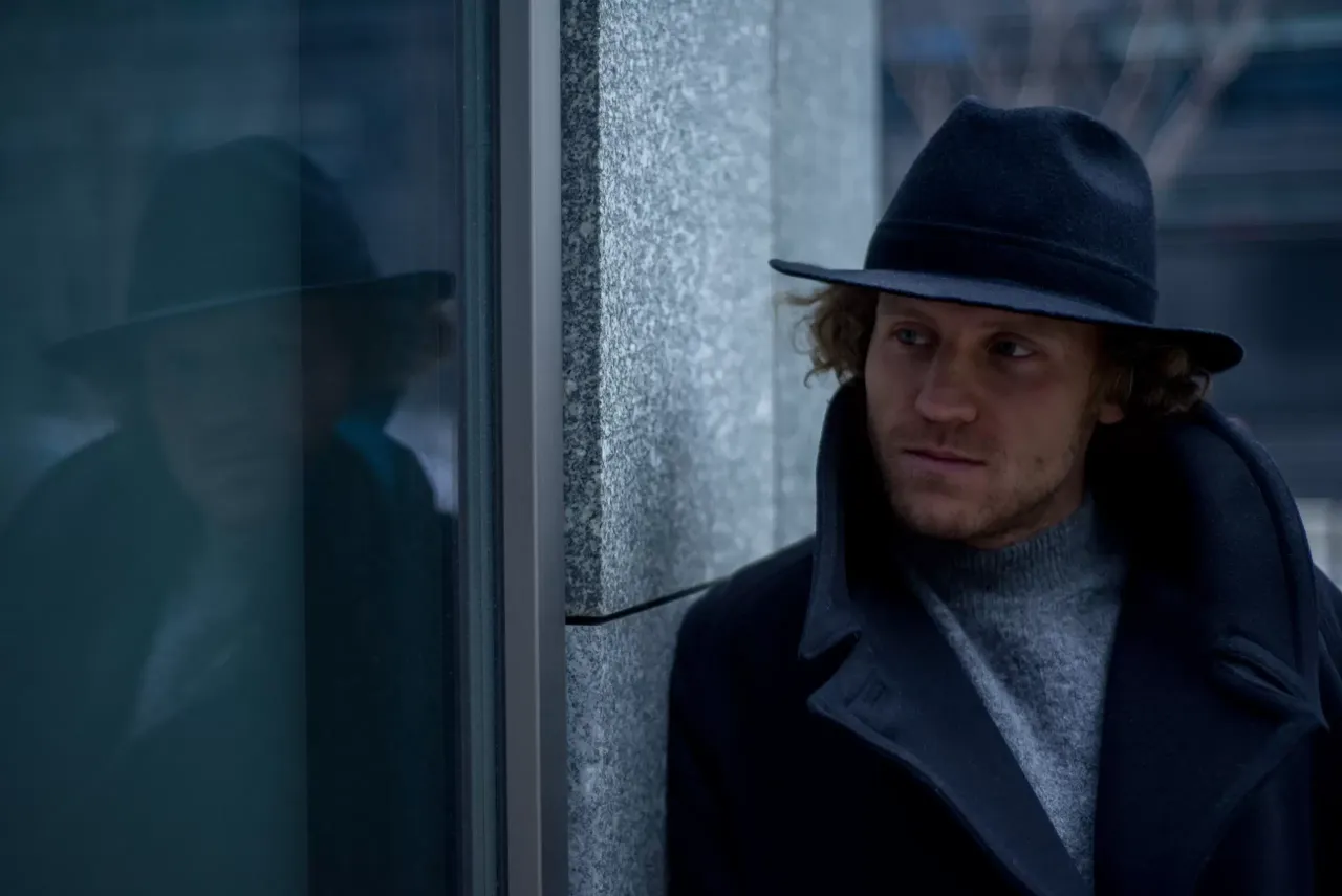 Mężczyzna zdejmujący kapelusz w pomieszczeniu