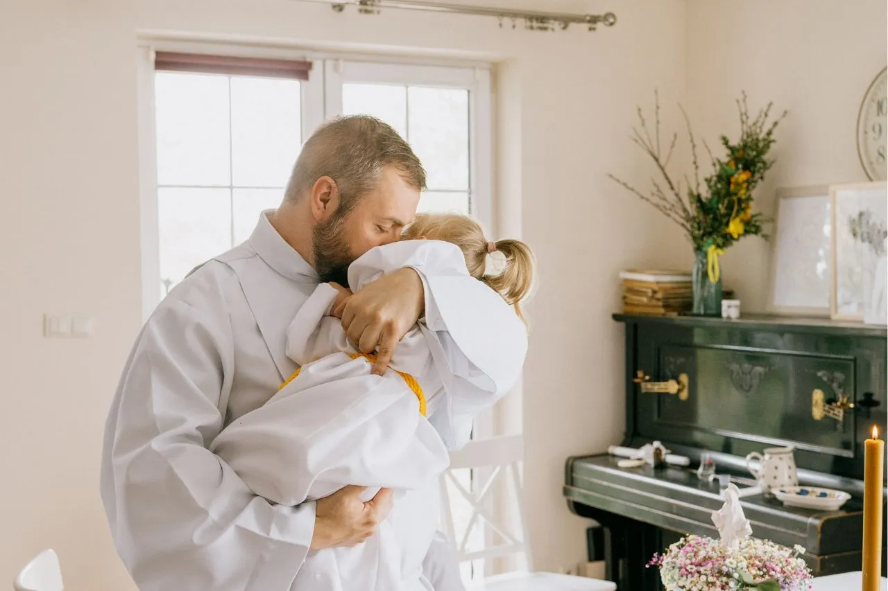 dziecko w albie z rodzicami przed kościołem