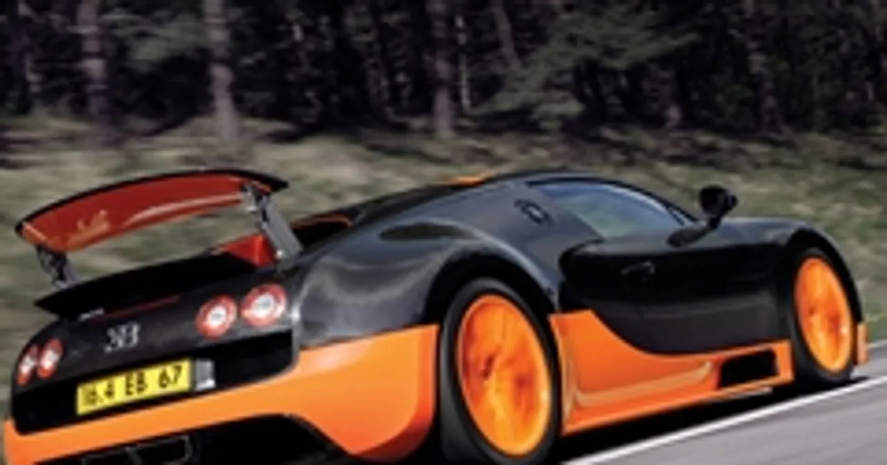 Czarny Bugatti Veyron z pomarańczowymi akcentami pędzi po drodze.