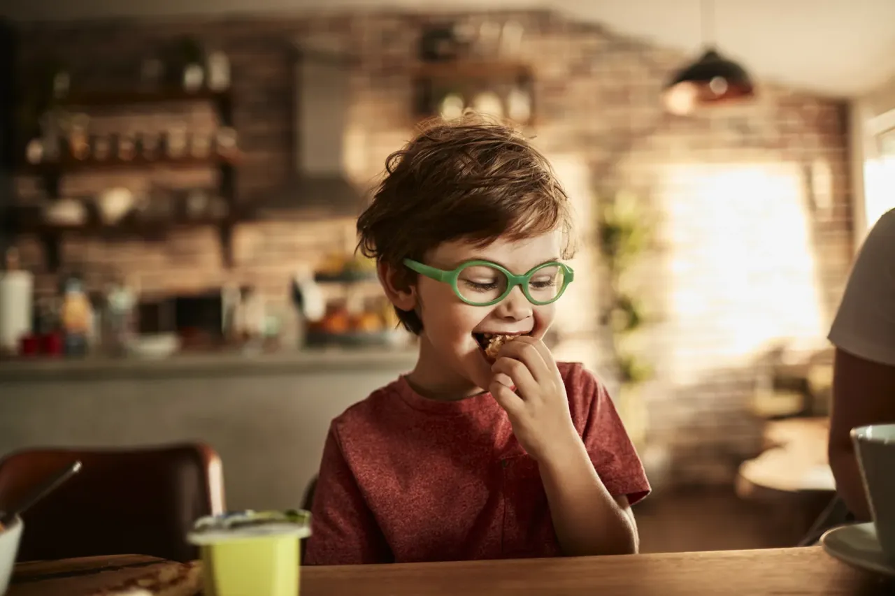 Chłopiec z astygmatyzmem 0.5 w zielonych okularach je śniadanie. Czy nosić okulary?