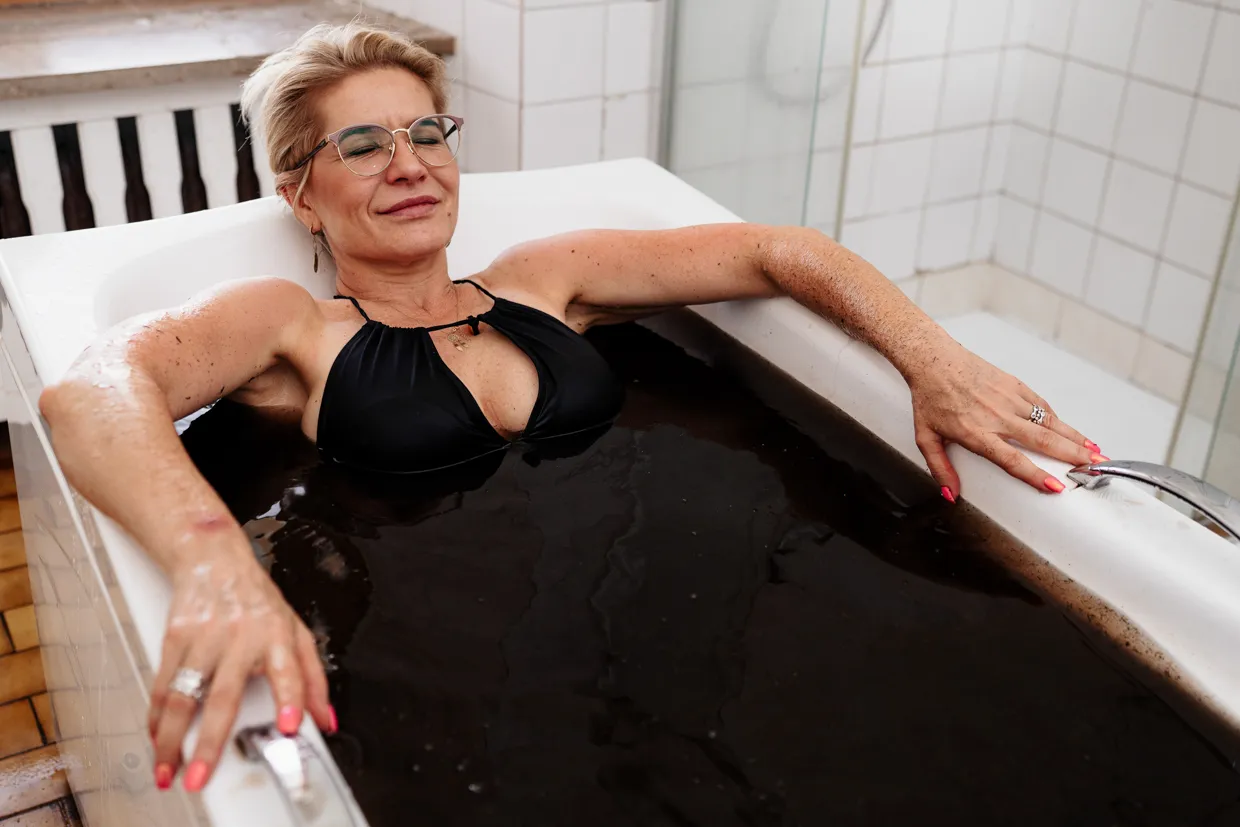 Kobieta relaksuje się w kąpieli borowinowej. Sprawdź promocje w sanatoriach Busko Zdrój!