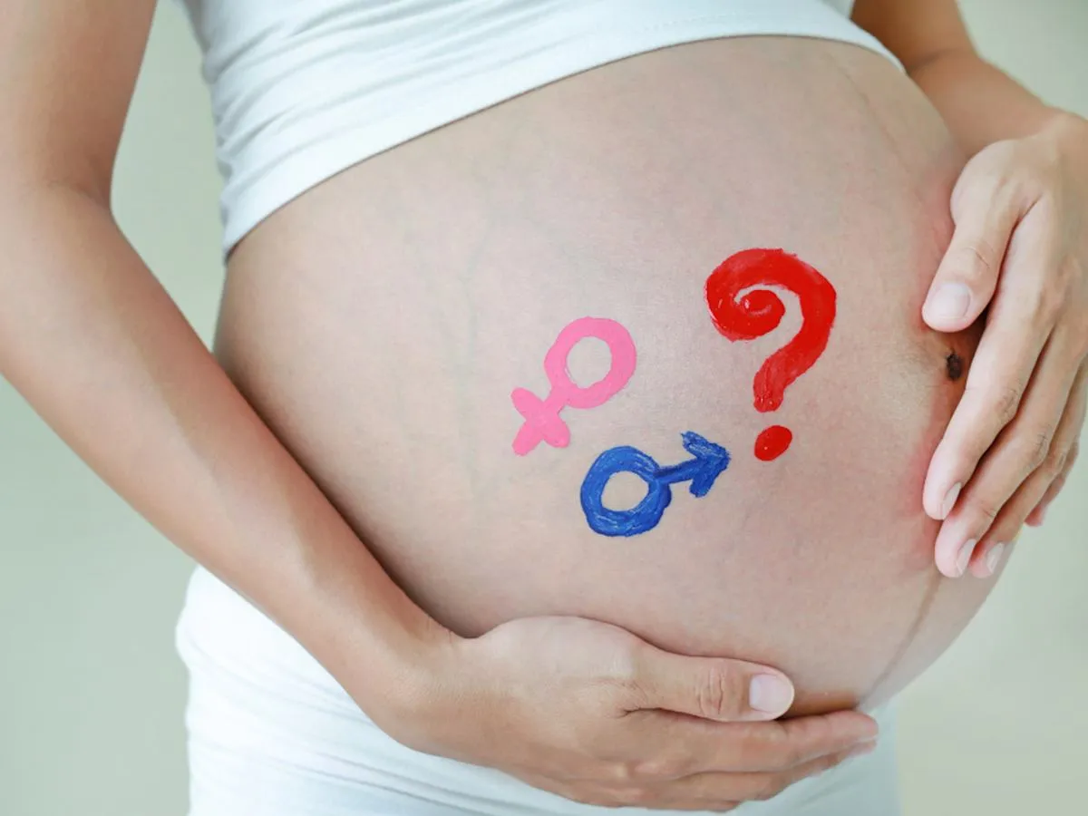 Kobieta w ciąży dotykająca brzucha, obok chiński kalendarz płci