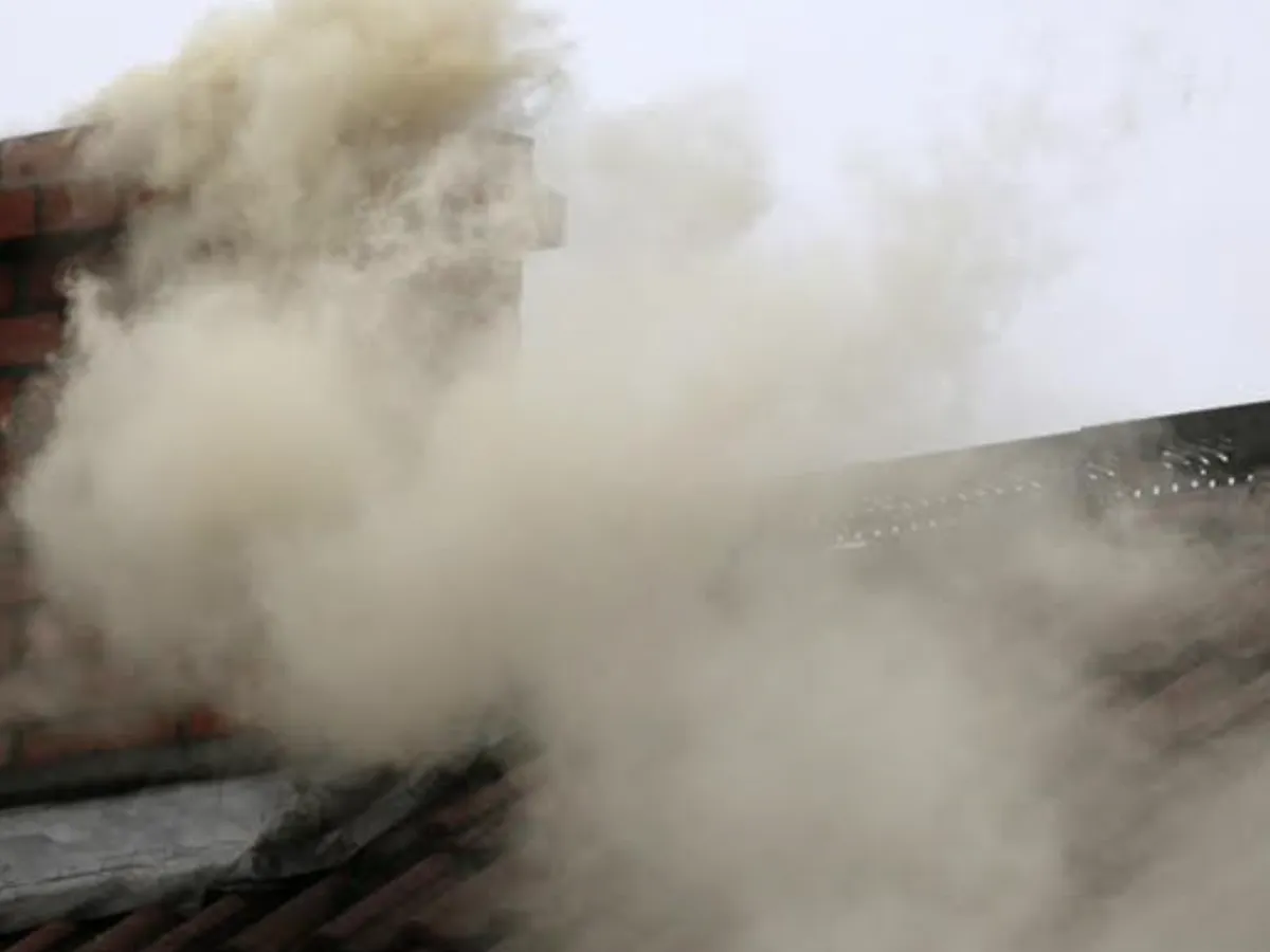 Gęsty dym wydobywa się z ceglanego komina, unosząc się nad dachem. Zastanawiasz się, jak poprawić ciąg w kominie?