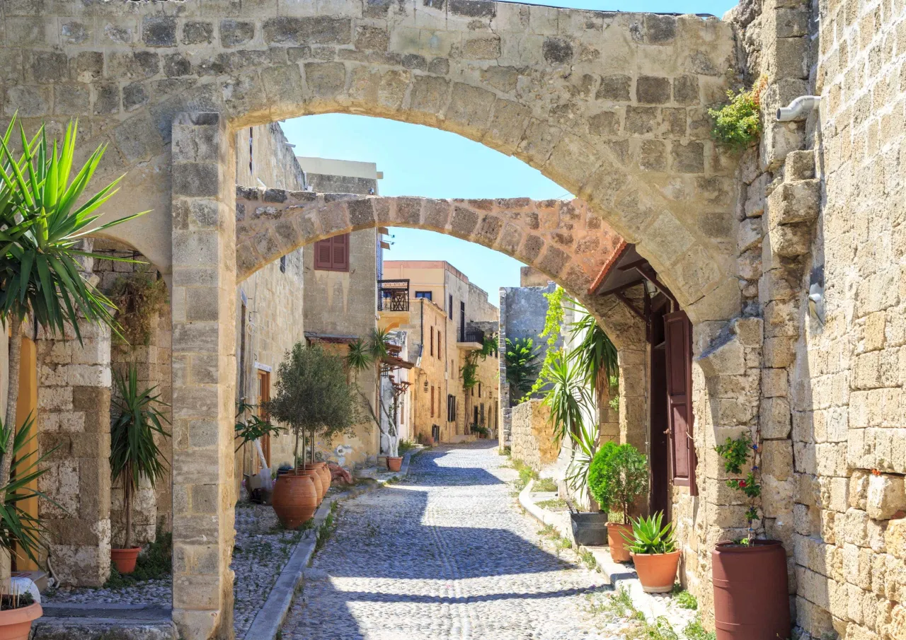Kamienna uliczka z łukami i donicami z roślinami, jedno z najpiękniejszych miejsc na Rodos.