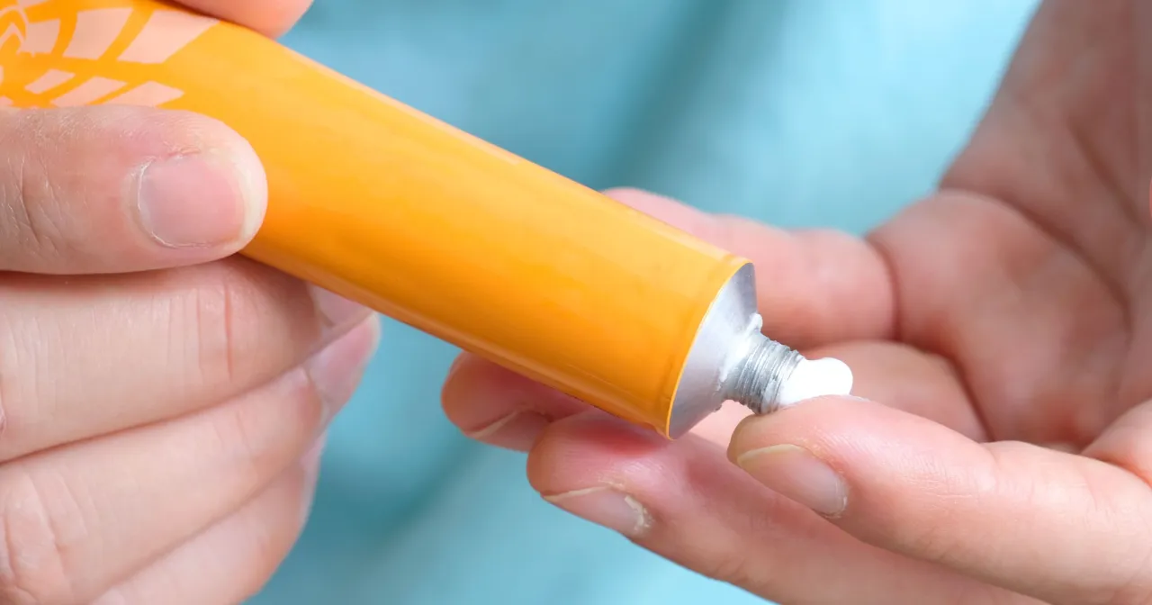 Tanie kosmetyki z apteki które działają cuda. Krem z pomarańczowej tubki na palcu.