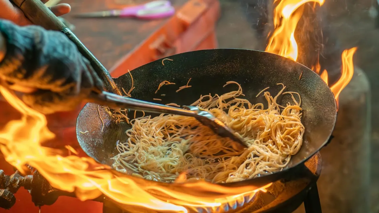 Makaron smażony na ogniu w woku, przygotowywane tajskie przekąski.