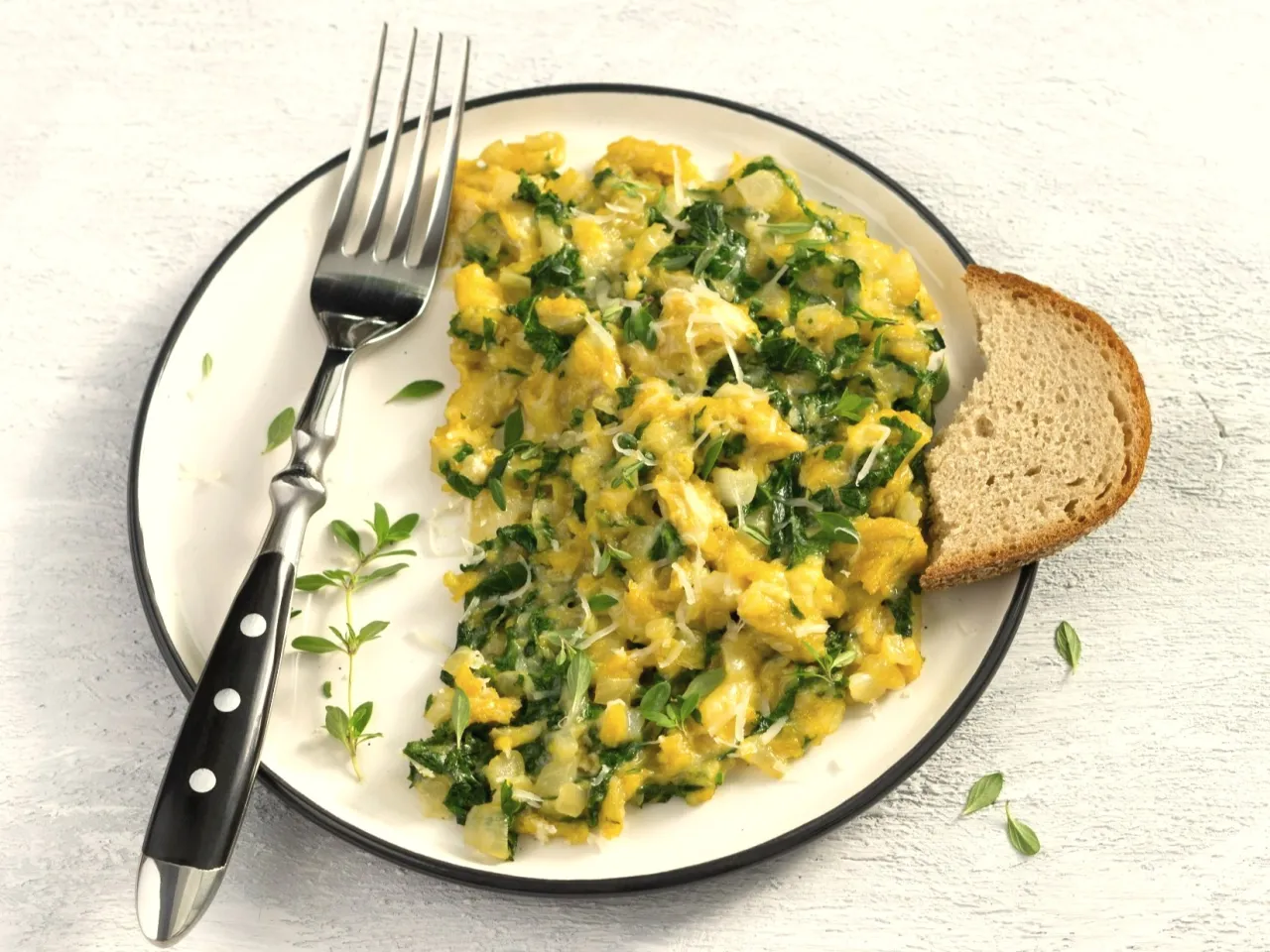 Jajecznica z ziołami i serem, podana z chlebem. Czy jajecznica jest dietetyczna? Zależy od dodatków!