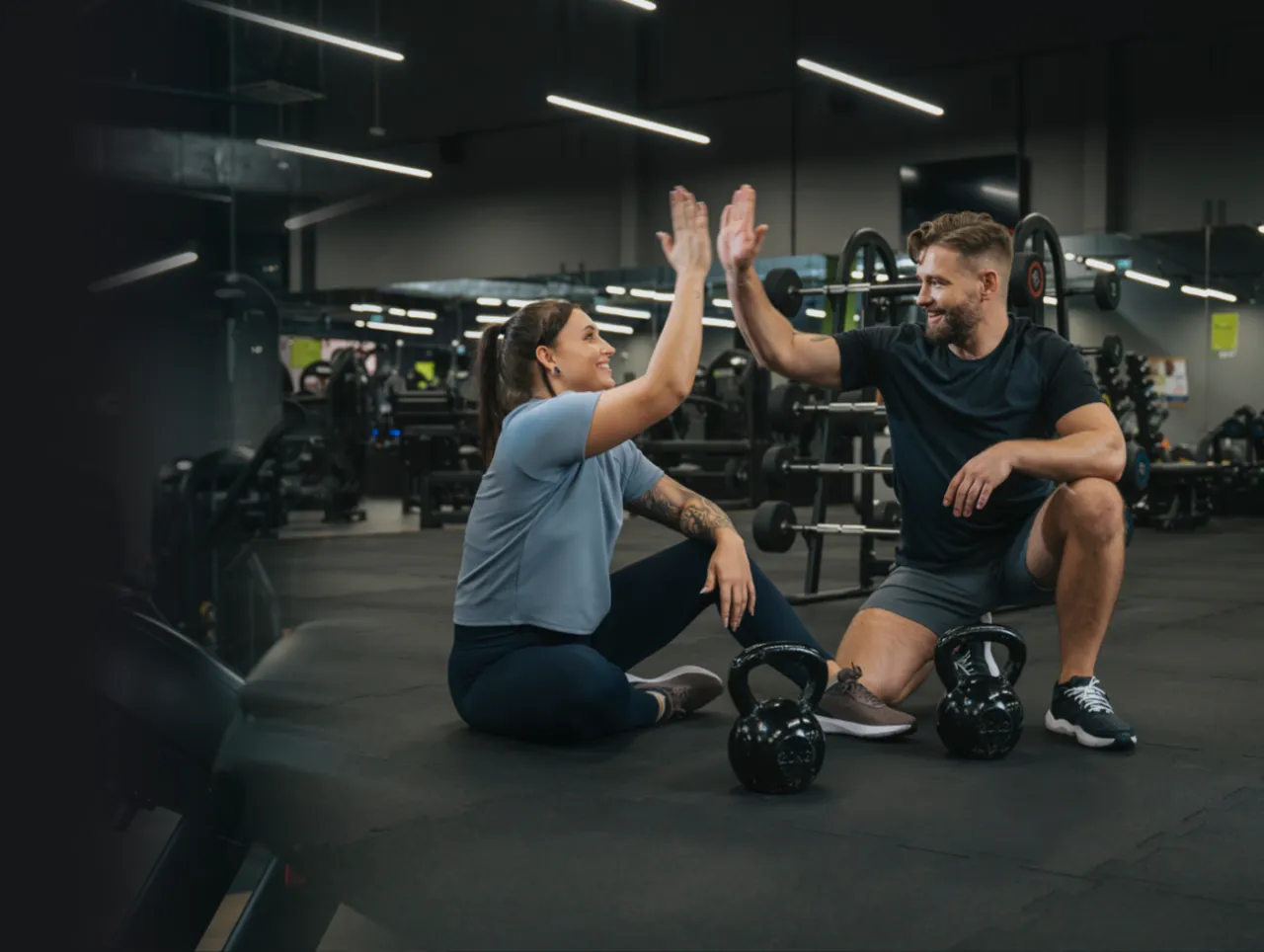 Para zacząć ćwiczenia na siłowni, potrzebujesz motywacji i dobrego planu. Para daje sobie piątkę po udanym treningu.