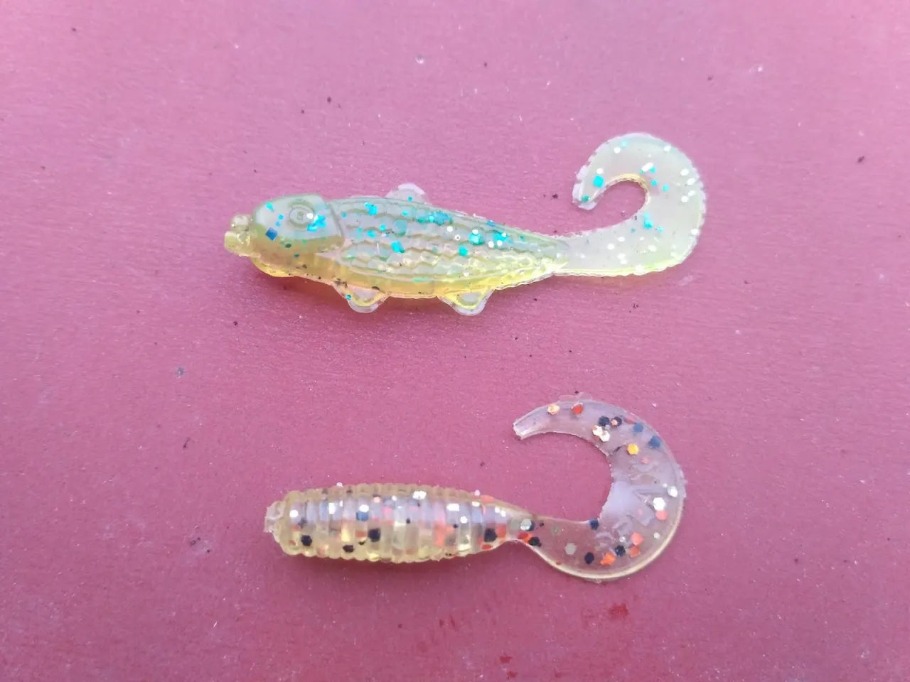 Dwie gumowe przynęty wędkarskie, imitujące rybki, gotowe na boczny trok na rzece.