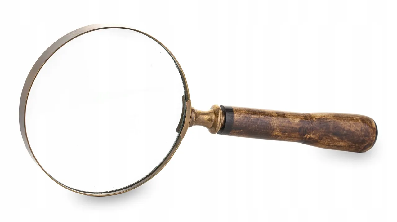 Lupa powiększająca mały druk na umowie lub rachunku, symbolizująca ukryte koszty