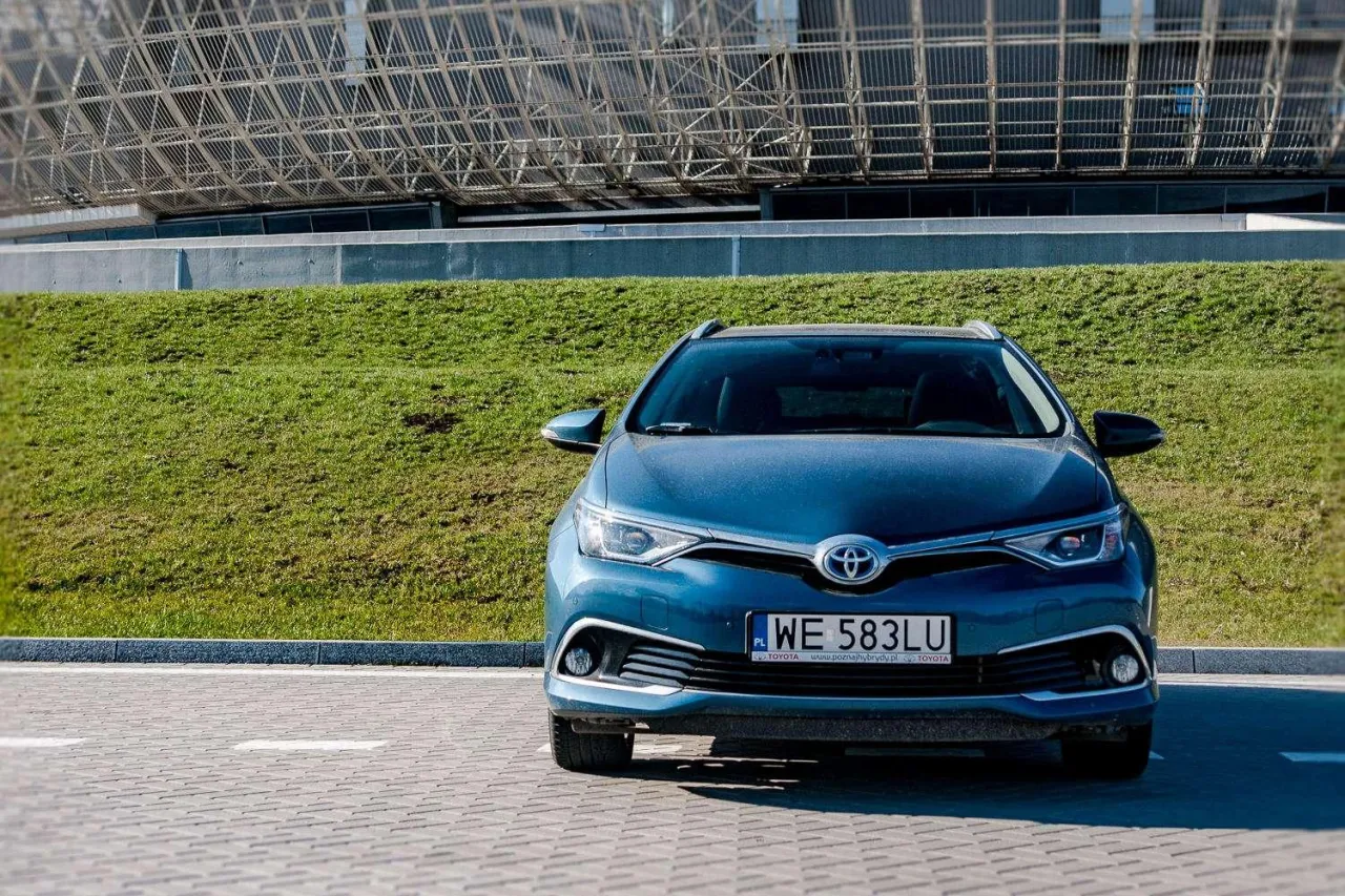 Niebieska Toyota Auris Hybrid zaparkowana przed nowoczesnym budynkiem. Zastanawiasz się, ile pali Toyota Auris Hybrid?