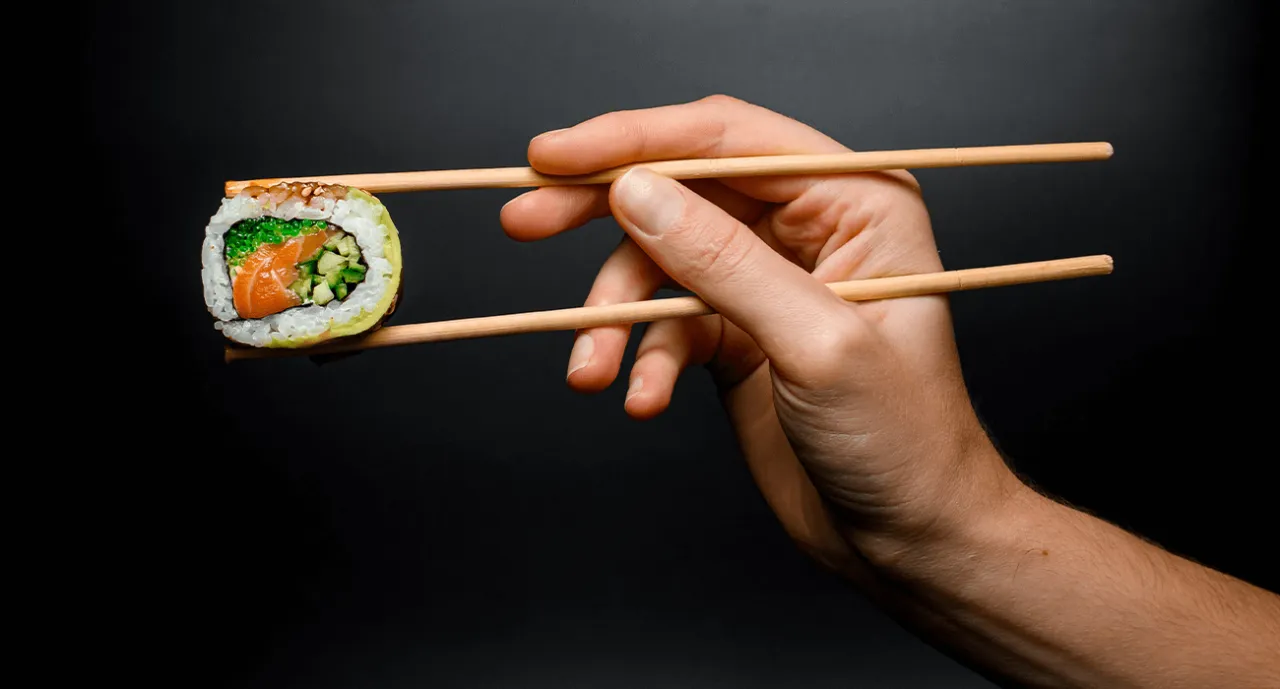 osoba jedząca sushi pałeczkami