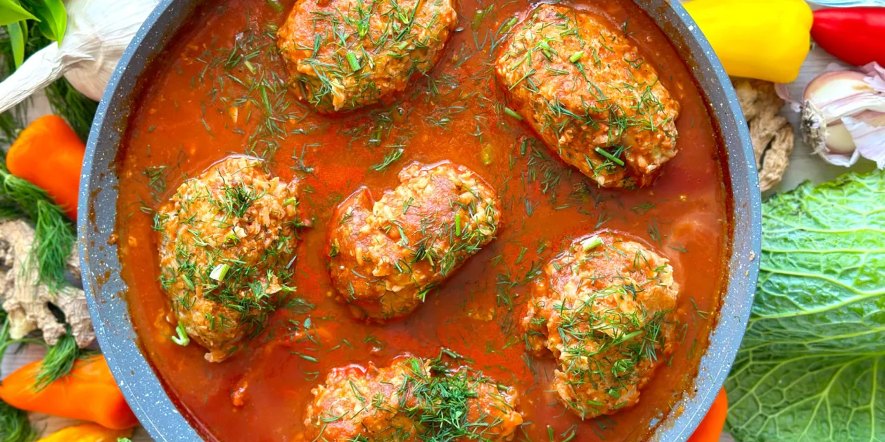 Gołąbki tradycyjne czy gołąbki bez zawijania? W garnku duszony sos pomidorowy z gołąbkami, posypane koperkiem. Obok papryka, kapusta i czosnek.