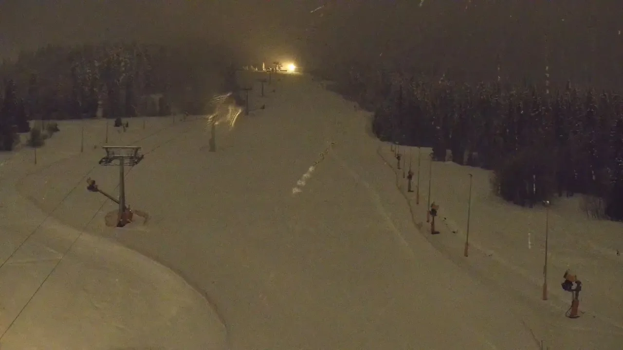 Widok z białka tatrzańska webcam nocą. Ośnieżony stok z wyciągiem krzesełkowym i armatkami śnieżnymi.