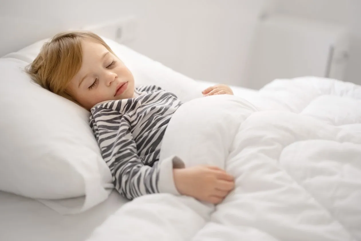 dziecko śpiące na materacu z prawidłową postawą kręgosłupa