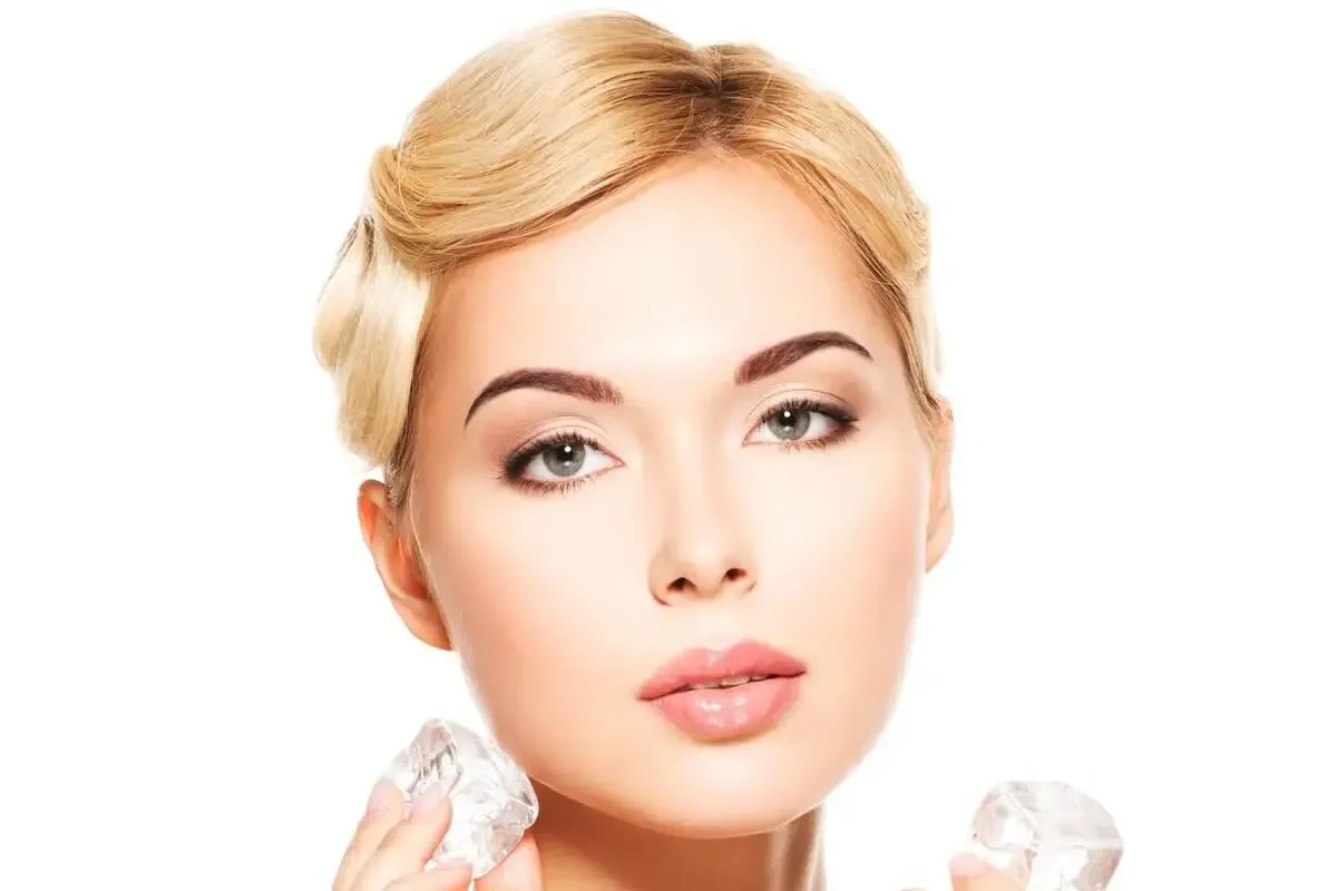 kobieta przykładająca l&oacute;d do pryszcza na twarzy