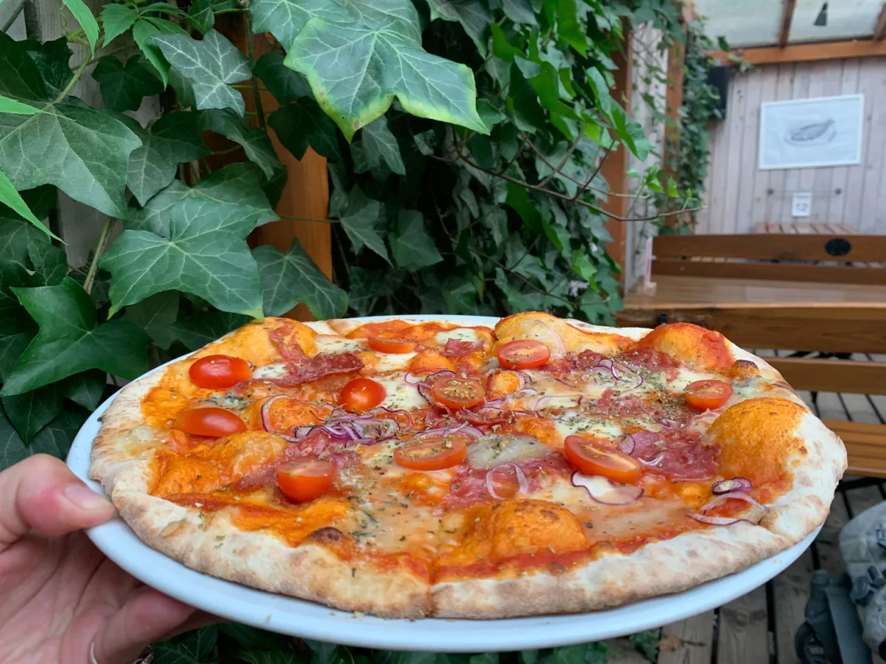 Pyszna pizza z pomidorkami i salami, idealna na pytanie gdzie zjeść w Dębkach.