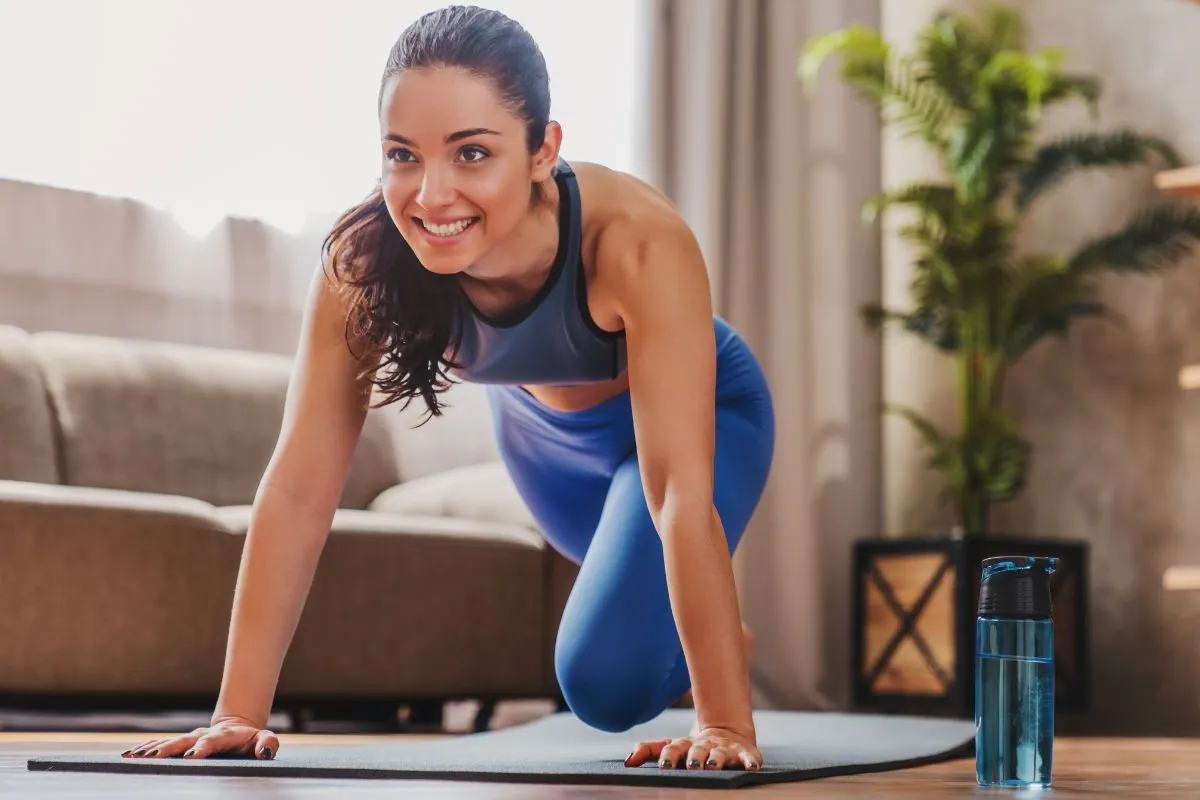 Uśmiechnięta kobieta ćwiczy pilates w domu. Pilates na co pomaga? Wzmacnia mięśnie, poprawia postawę i elastyczność.