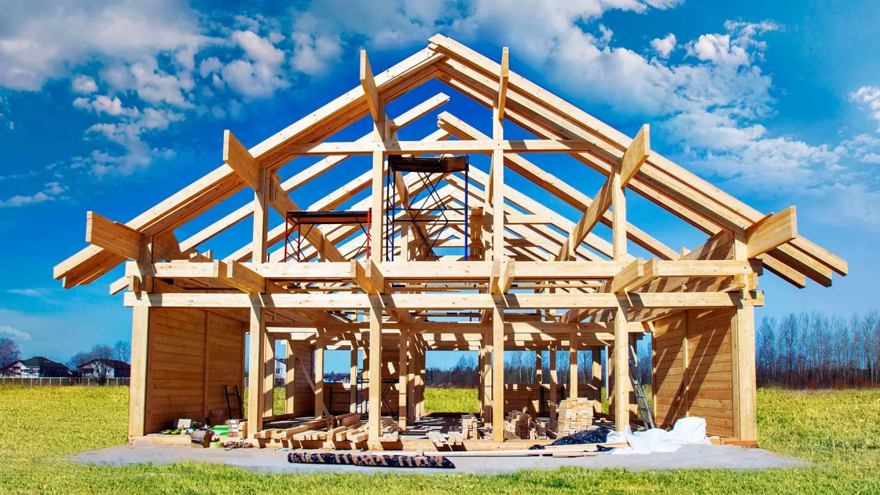 Budowa domu szkieletowego. Zastanawiasz się jakie firmy polecacie? Oto konstrukcja z drewna pod błękitnym niebem.