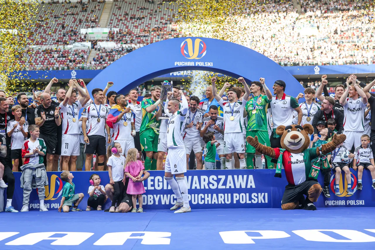 Piłkarze Legii Warszawa świętują zwycięstwo w Pucharze Polski. Złote konfetti i radość na twarzach zawodnik&oacute;w.