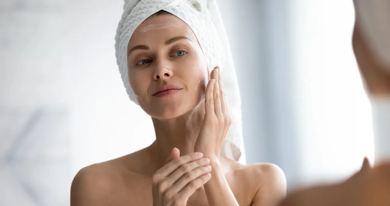 kobieta nakładająca krem do twarzy z filtrem SPF