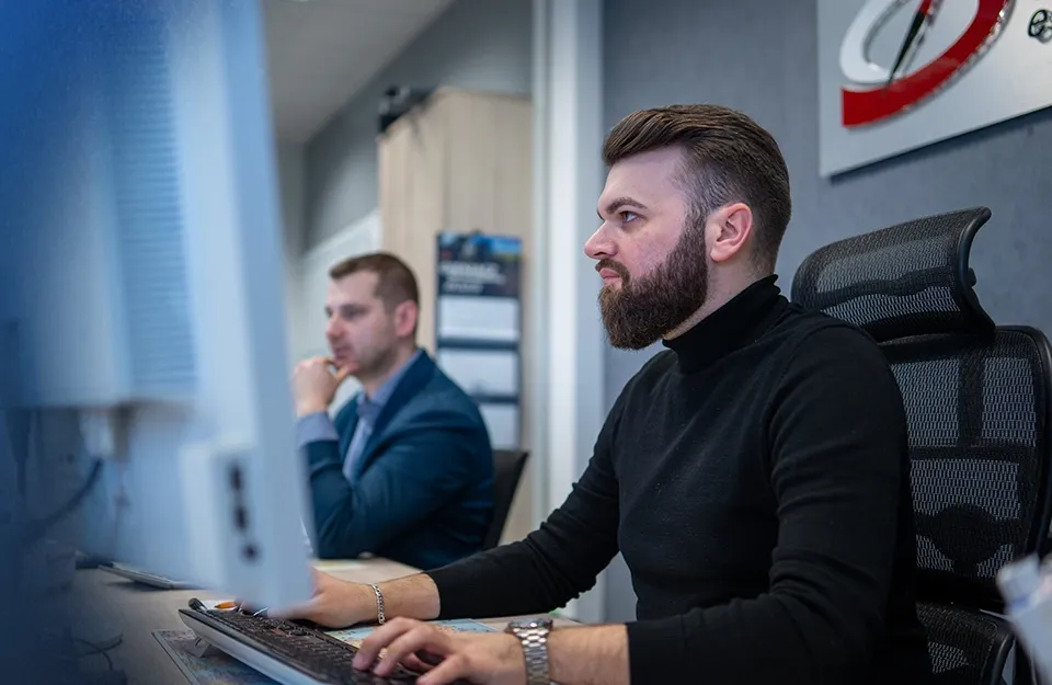 Spedytor międzynarodowy przy biurku z mapą świata i komputerem