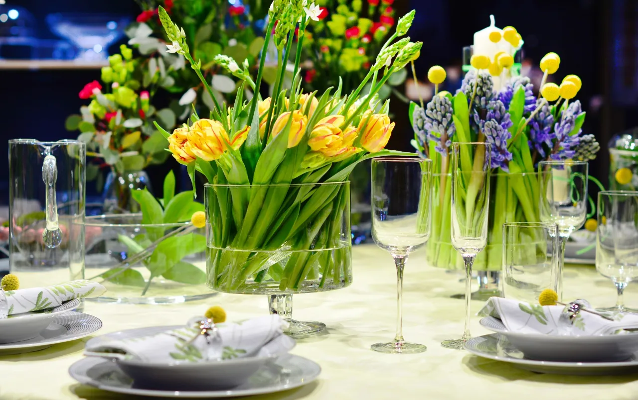 St&oacute;ł nakryty do świątecznego posiłku, pełen wiosennych kwiat&oacute;w i eleganckich naczyń. Wspaniałe pomysły na dekoracje wielkanocne.
