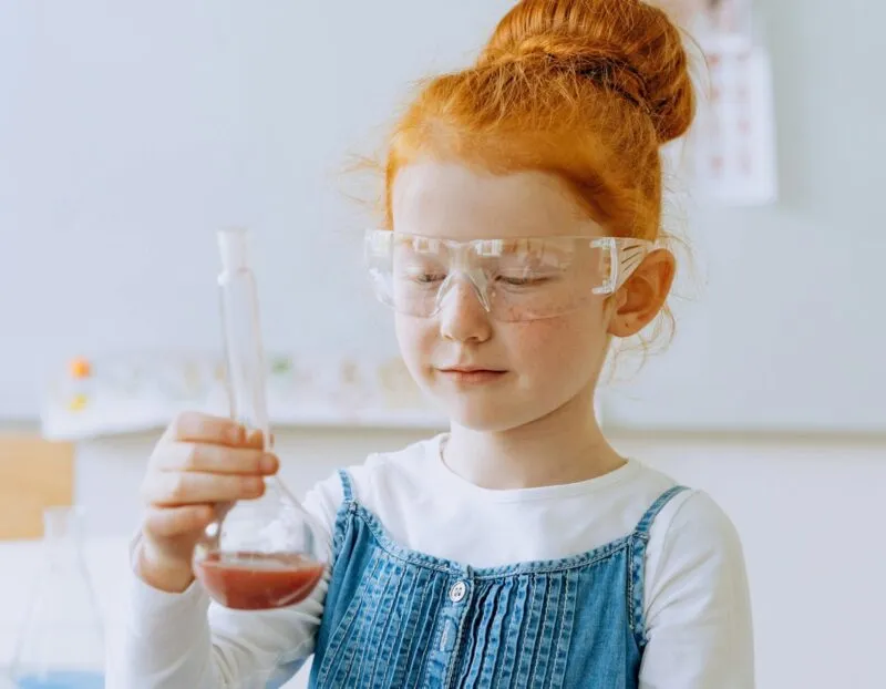 dzieci w okularach ochronnych robiące eksperymenty chemiczne