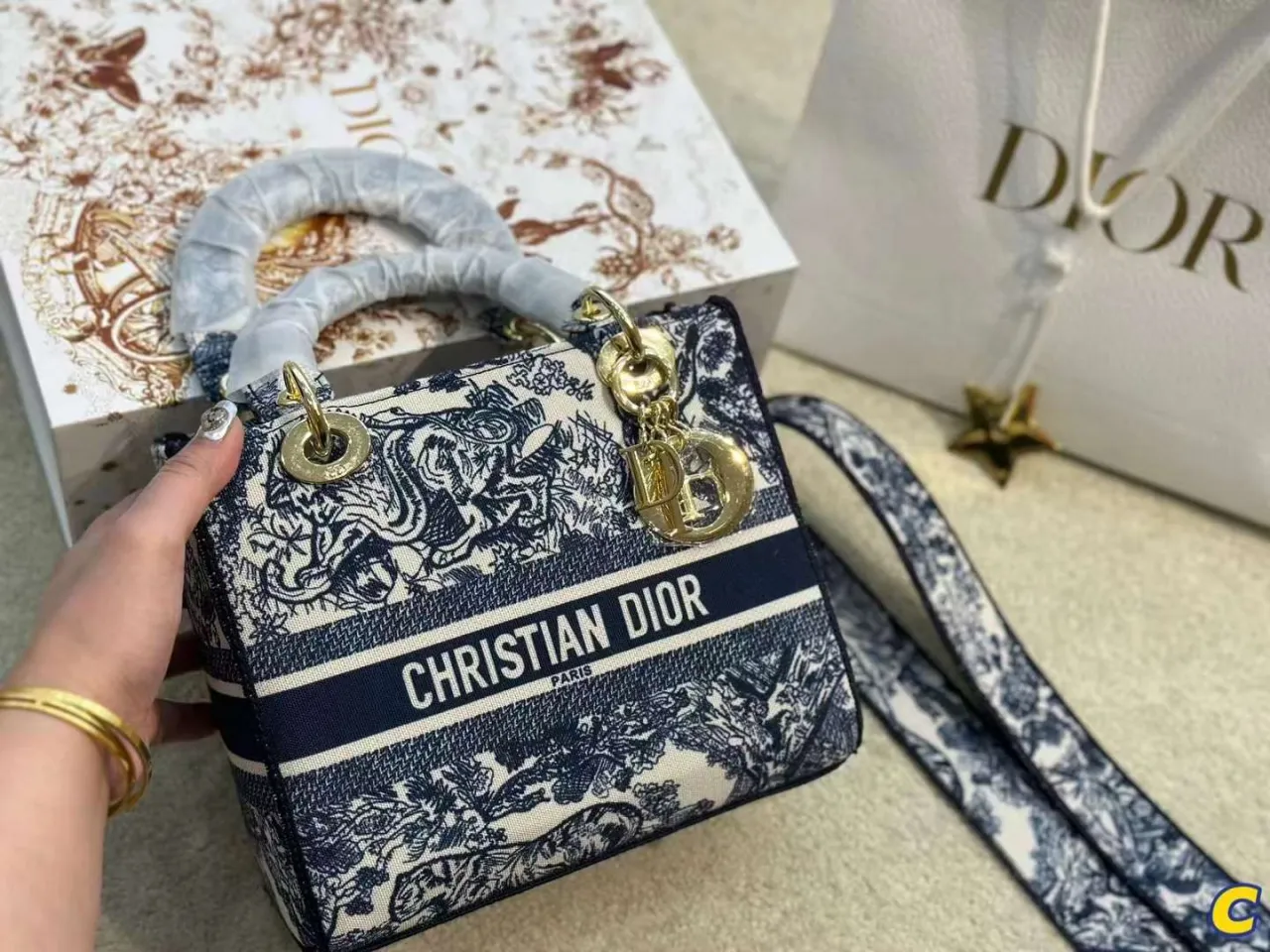 Elegancka christian dior torebka w granatowo-białe wzory, z logo marki i złotymi elementami.