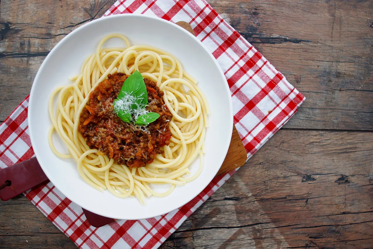 Pyszne spaghetti bolognese z bazylią i parmezanem na talerzu. To pokazuje, co można zrobić z makaronu spaghetti.