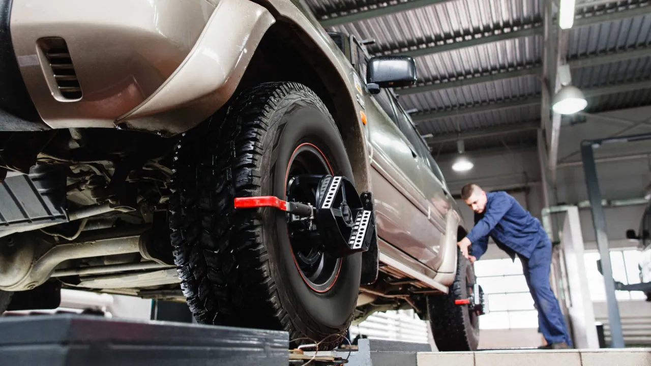 Mechanik ustawia zbieżność k&oacute;ł w samochodzie terenowym, używając specjalistycznego sprzętu. Dowiedz się, jak samemu ustawić zbieżność.