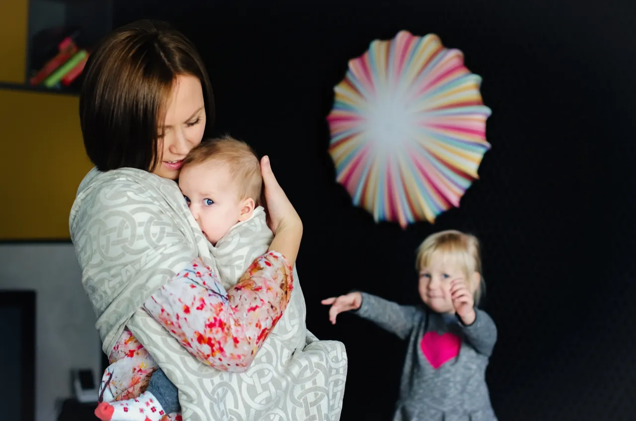 Rodzic noszący dziecko w chuście, uśmiechnięty