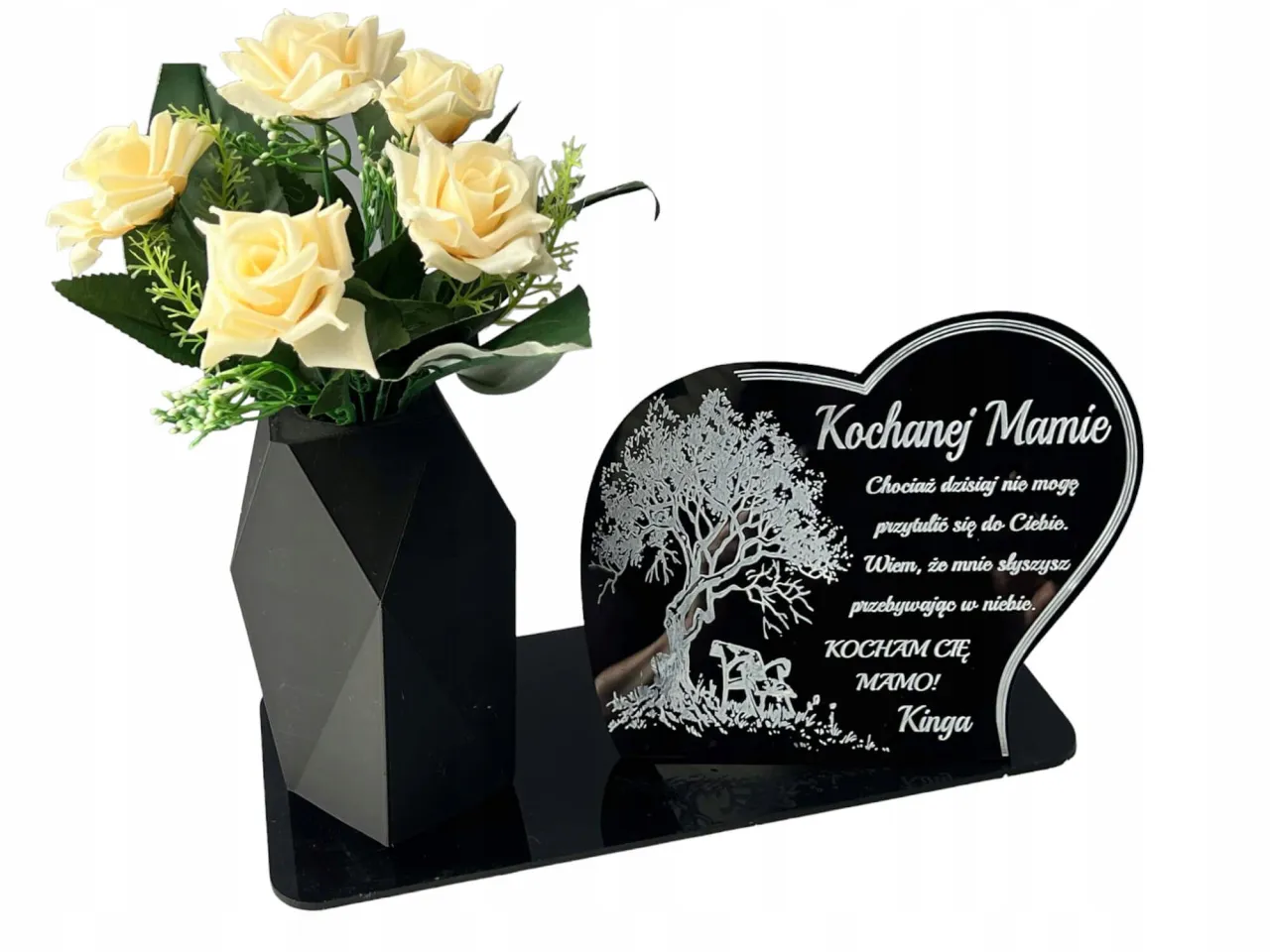 Pomnik nagrobny z wygrawerowanym cytatem, w tle znicze i kwiaty