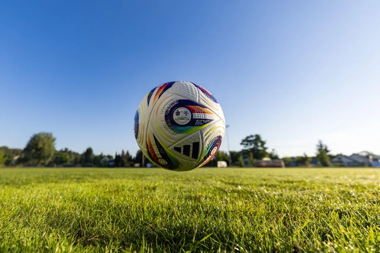 Piłka do gry w piłkę nożną unosi się nad zieloną trawą. Na piłce widnieje logo PKO Bank Polski Ekstraklasa, sugerując, ile kolejek do końca sezonu.
