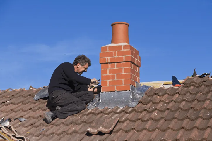 Kominiarz przy pracy naprawiający komin