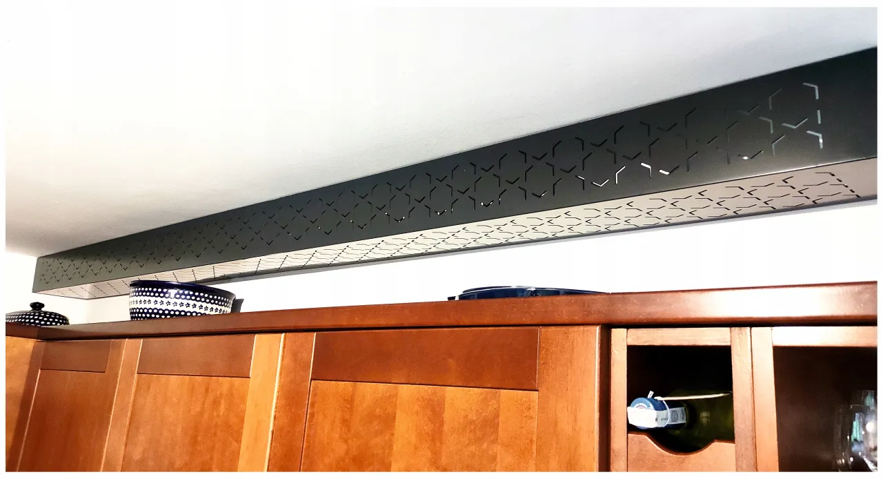 Elegancka zabudowa rur gazowych z ażurowym wzorem nad drewnianymi szafkami kuchennymi.