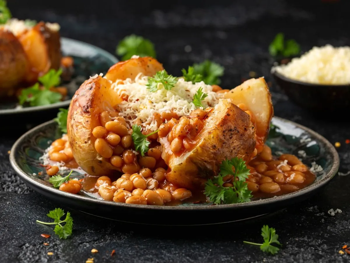 Pyszna fasolka w sosie pomidorowym w pieczonym ziemniaku, posypana serem i natką pietruszki. Idealne danie, co można zjeść na obiad.