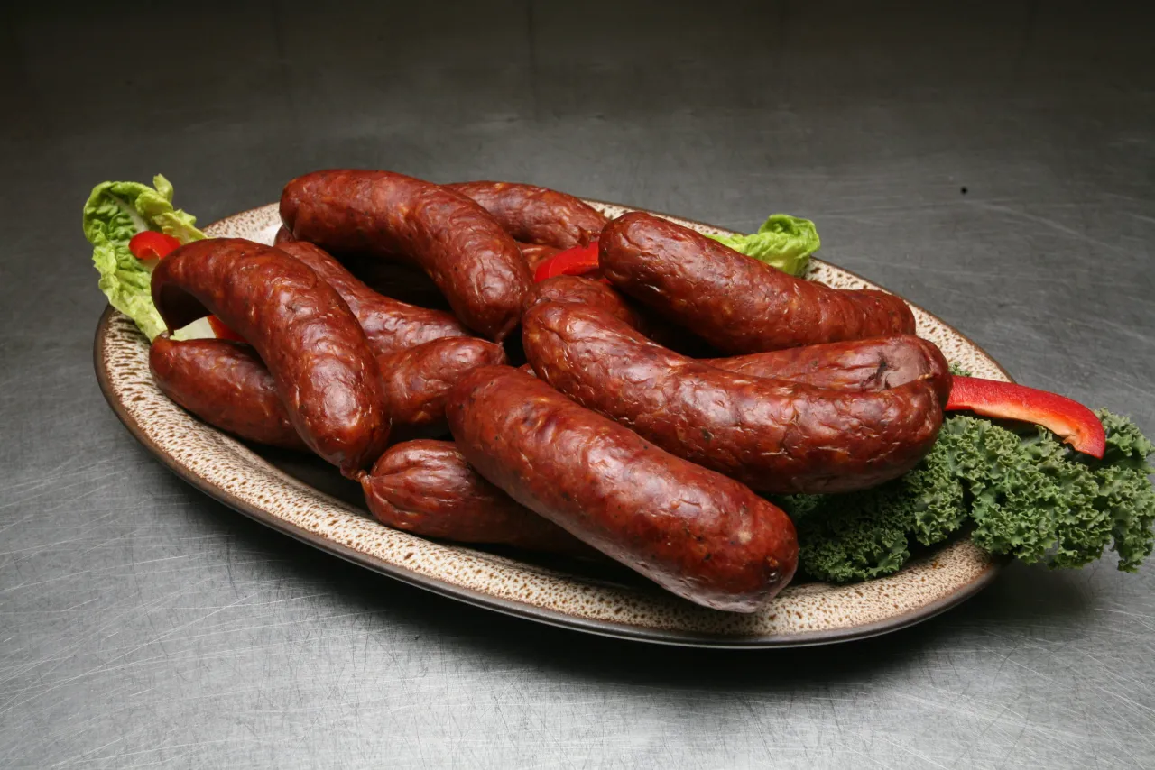 Talerz pełen kiełbas, sałaty i papryki. Czy myśliwy jako osoba prywatna może sprzedać mięso?