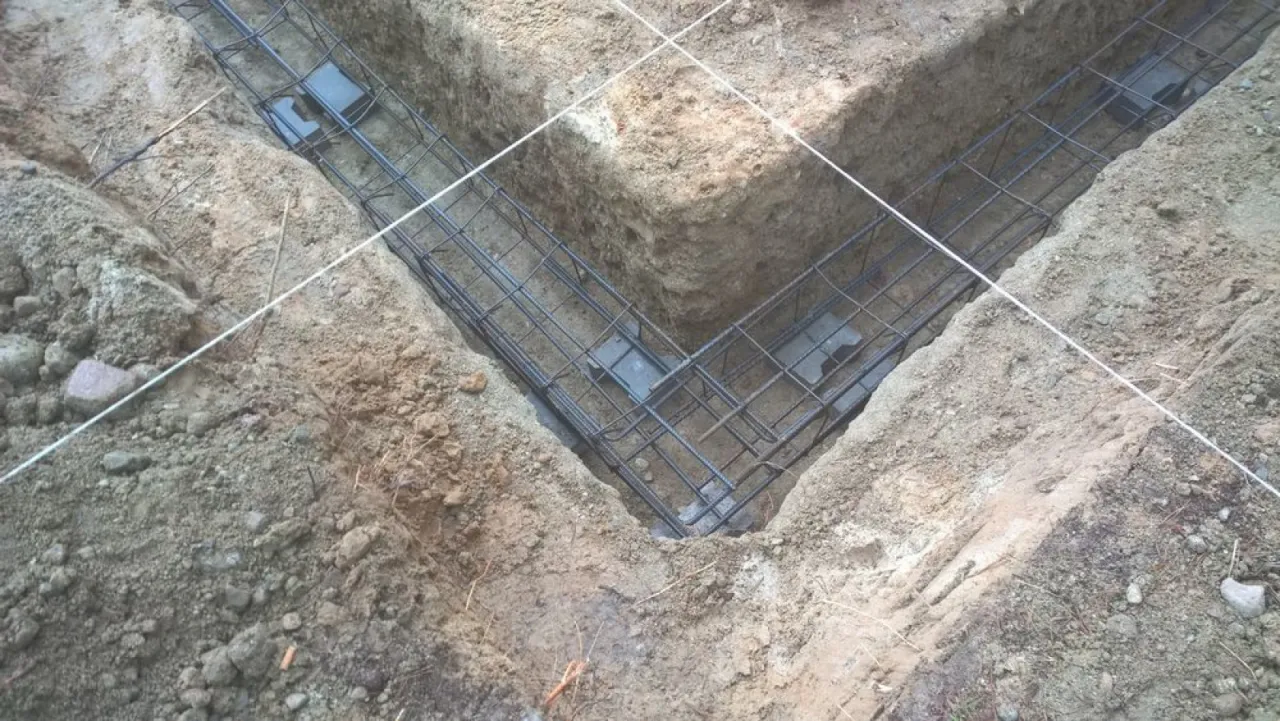 Zbrojenie fundamentów w wykopie, widoczne podkładki pod zbrojenie zapewniające odpowiedni otuliny betonowej.