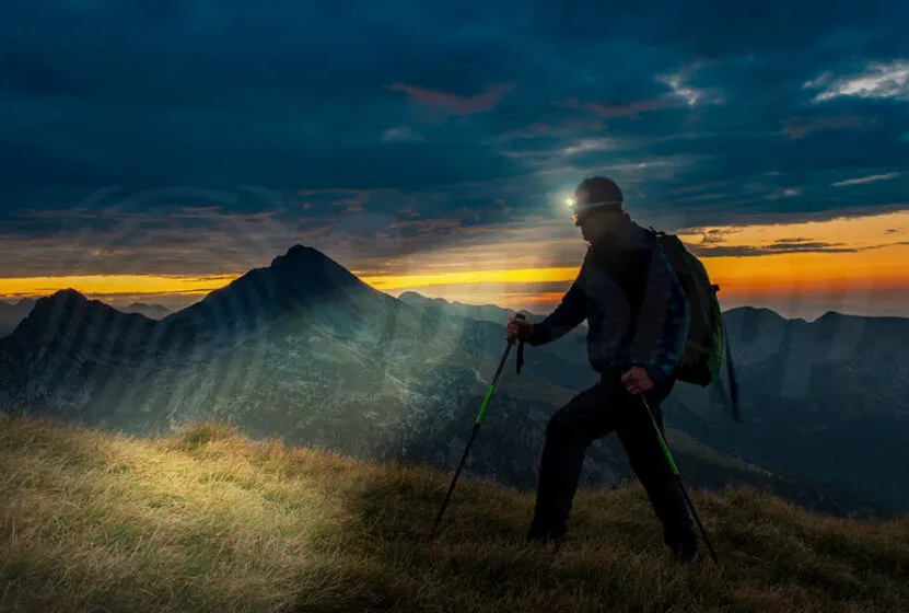 osoba używająca czołówki podczas nocnego trekkingu w górach