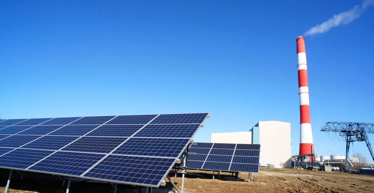 Panele słoneczne i czerwono-biały komin z dymem. To obraz przyszłości energetycznej, wspieranej przez program Energia Plus.