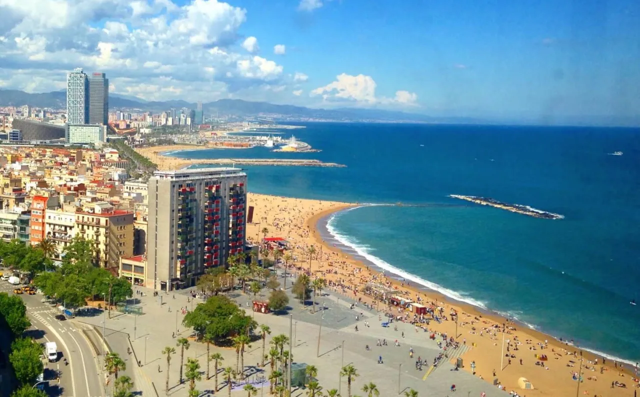 Widok na Barcelonę z plażą i morzem. Idealne miejsce, by zastanowić się, gdzie najlepiej nocować w Barcelonie, blisko plaży.