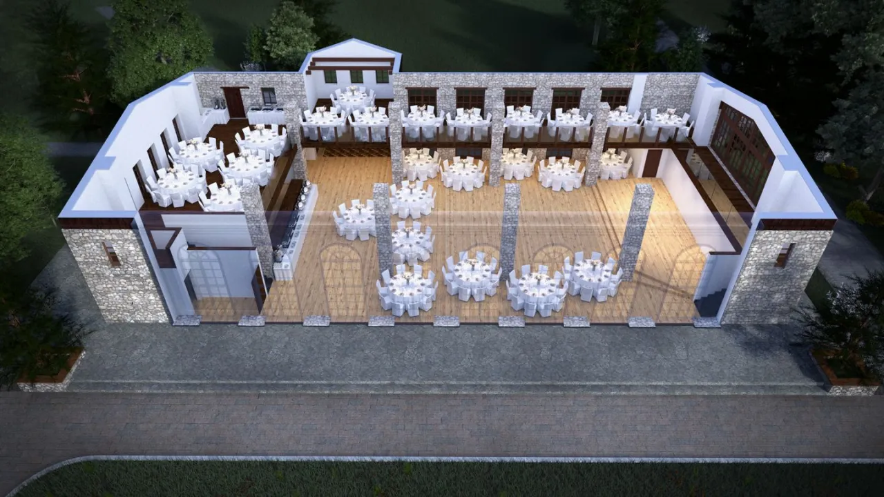 Widok z lotu ptaka na dwór w Tomaszowicach. Wnętrze przygotowane na przyjęcie, z licznymi okrągłymi stołami nakrytymi białymi obrusami.