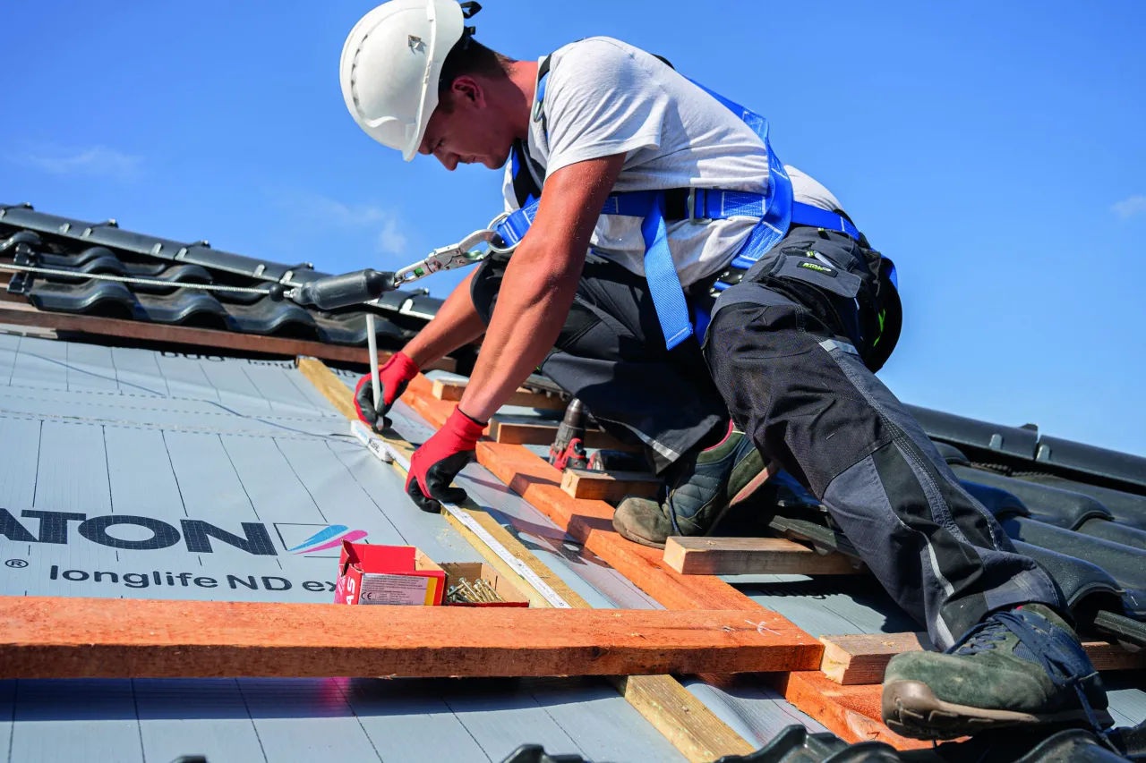 dekarz na dachu z wyposażeniem ochronnym