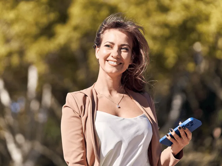 Kobieta przeglądająca aplikację randkową na telefonie, z uśmiechem