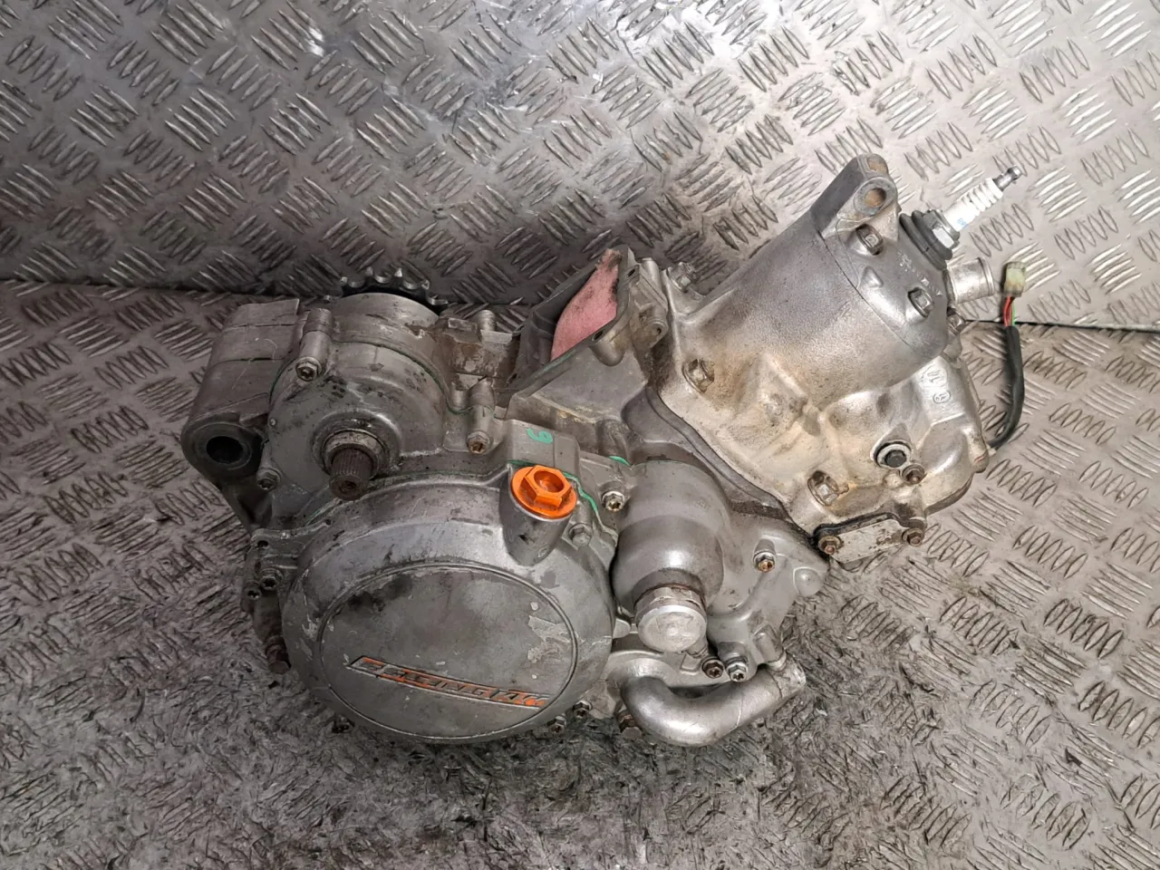 Silnik Husqvarna 125, gotowy do montażu. Widoczna świeca zapłonowa i elementy obudowy.