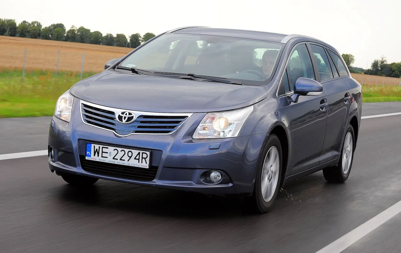 Szary kombi Toyota Avensis na drodze. Kierowca za kierownicą. Jaki silnik? To pytanie zadaje sobie wielu.