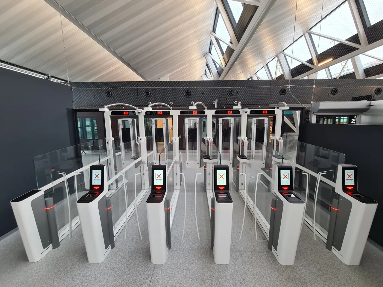 Nowoczesne bramki na lotnisku, pokazujące, jak działają, z czerwonymi krzyżykami na ekranach.