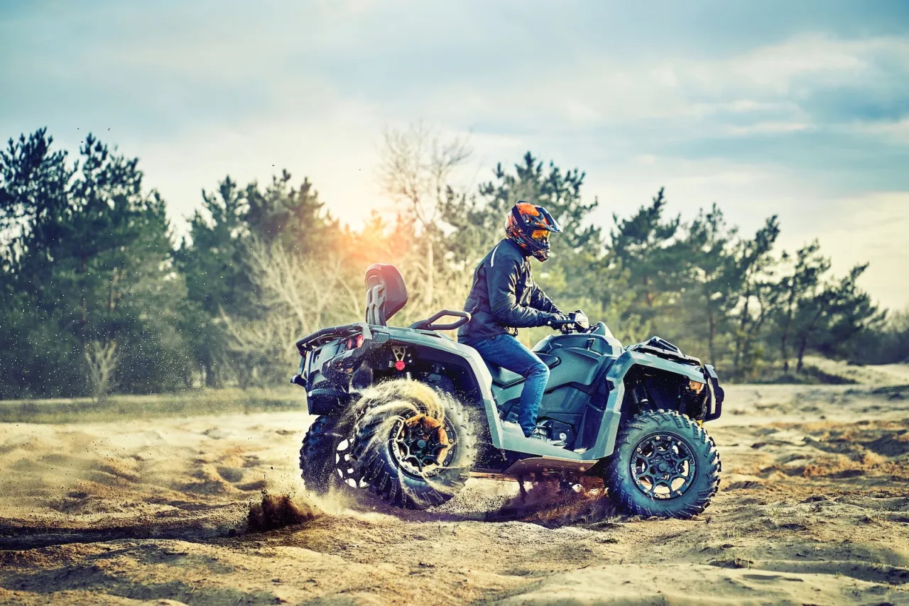 Mężczyzna w kasku jedzie quadem po piaszczystym terenie. Zastanawiasz się, jakie prawo jazdy na quada 125?